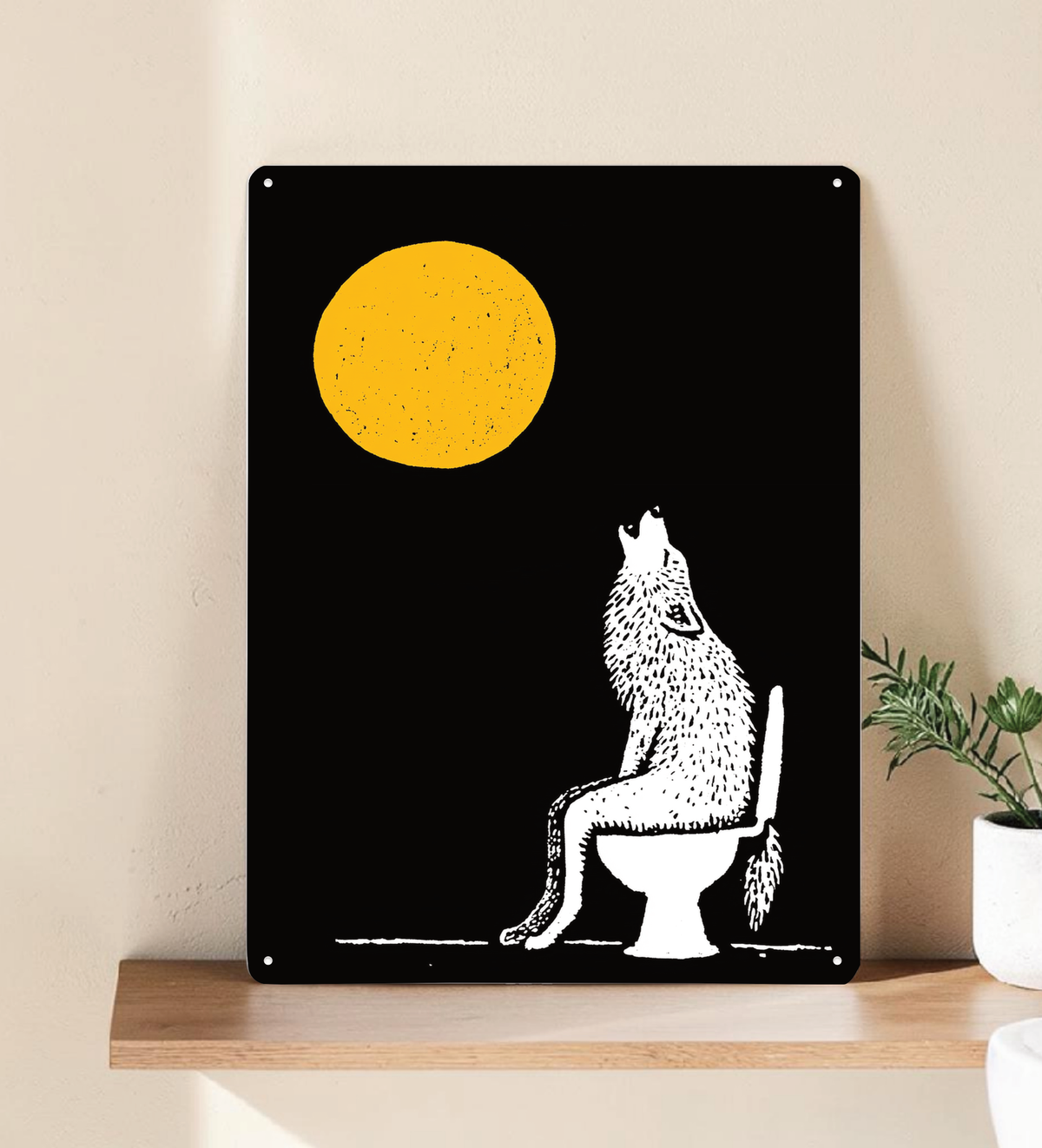 Ein hochformatiges, schwarzes Metallschild steht dekorativ auf einem hellen Holzregal vor einer beigen Wand. Das Motiv zeigt einen großen, strukturierten gelben Vollmond und die weiße Silhouette eines Wolfs, der auf einer Toilette sitzt und nach oben heult. (Referenz: 1 Bild Metallschild Badezimmer Wolf Mond.jpg)