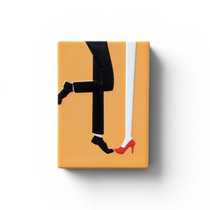 "Rechteckiger Keramik-Kühlschrankmagnet (7x5 cm) mit einem 3D-Relief. Zu sehen sind die Beine eines Paares: eine Person in roten High Heels und Herzchensocken, die andere in rot-weiß gestreiften Socken, auf hellem Hintergrund."