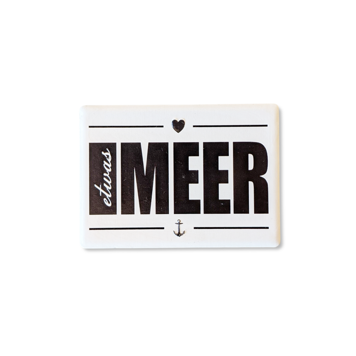 Rechteckiger Keramik-Kühlschrankmagnet (7x5 cm) im Querformat mit seidenmatter Glasur. Auf weißem Grund steht der schwarze Schriftzug 'etwas MEER' mit Anker und Herz-Symbol im fühlbaren 3D-Relief.