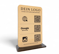 Personalisierter QR-Code Aufsteller aus hellem Holz mit schwarzem Standfuß, Logo-Gravur und drei QR-Codes für Website, Google-Bewertungen und Instagram.