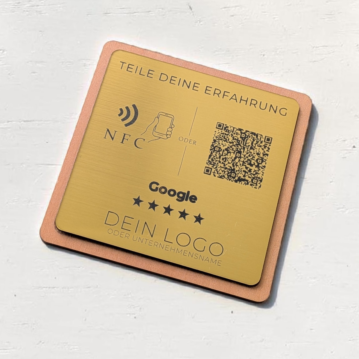 Ein quadratischer oder rechteckiger Tischaufsteller zur Kundenbewertung. Auf der Vorderseite befindet sich oben das farbige Google-Logo, gefolgt von der Aufforderung 'Bewerte uns auf Google'. Im Zentrum ist ein scannbarer QR-Code abgebildet. Unten rechts signalisiert ein Wellen-Symbol die integrierte NFC-Funktion zum kontaktlosen Scannen mit dem Smartphone.