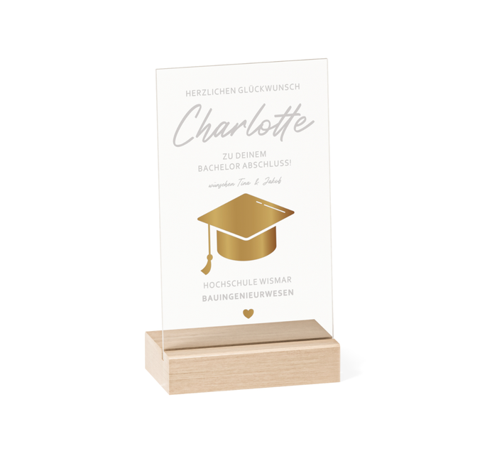 Transparenter Acrylglas-Aufsteller mit Holzsockel, personalisiert als Geschenk zum Abschluss. Zeigt goldene Doktorhut-Grafik, Namen, Studiengang und Hochschule in elegantem Design.