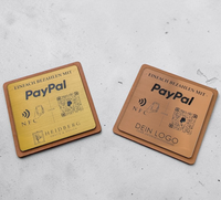 Quadratischer PayPal-Tischaufsteller aus dunklem Holz mit einer gravierten und gebürsteten Kunststoffplatte. Auf der Platte sind ein QR-Code, ein NFC-Symbol und das PayPal-Logo zu sehen, perfekt geeignet für kontaktlose Zahlungen auf einer Ladentheke.