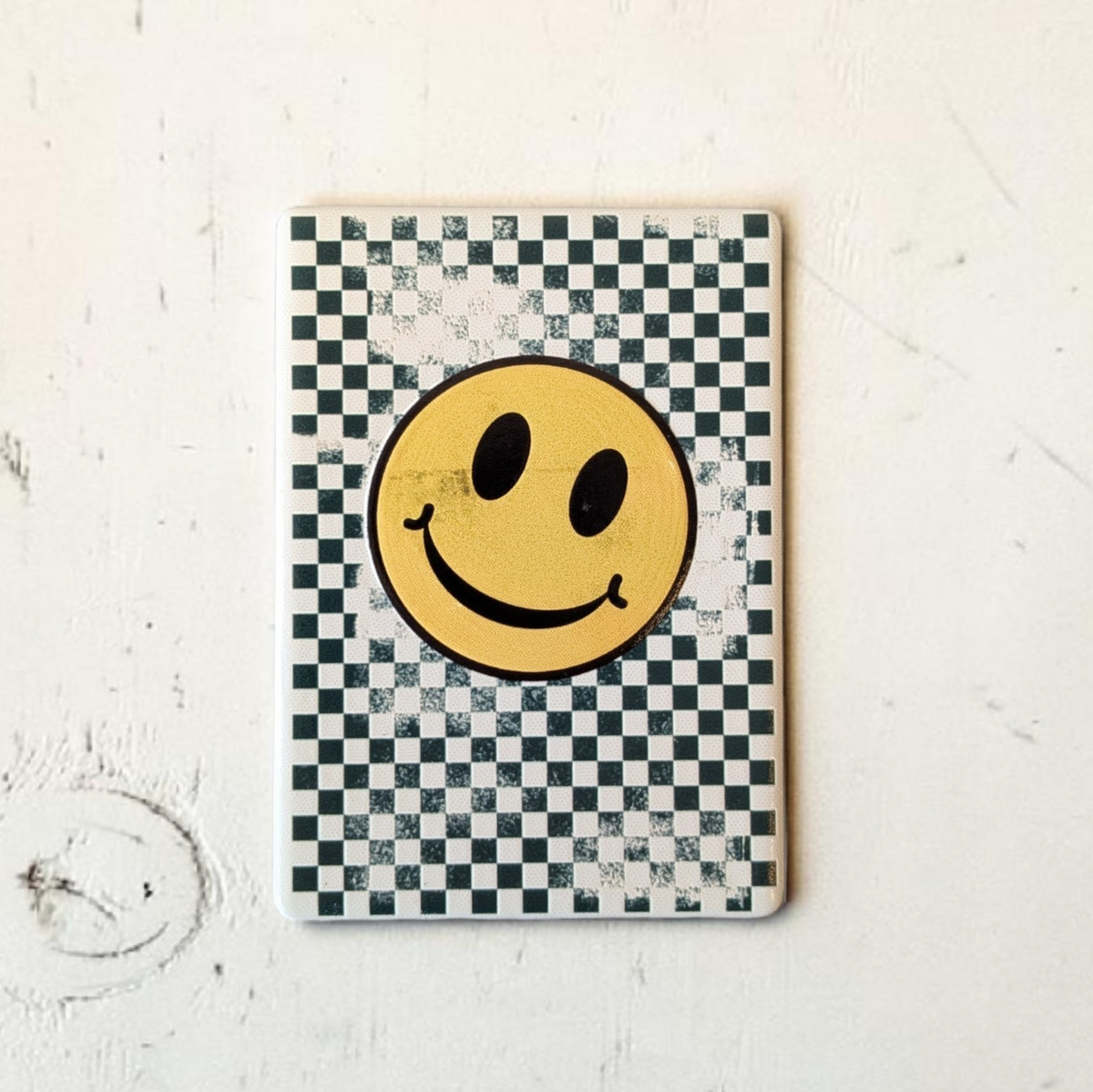 Rechteckiger weißer Keramikmagnet mit einem abstrahierten, gelben Smiley-Gesicht aus Quadraten. Die Oberfläche zeigt eine haptische Relief-Struktur und ein elegantes, seidenmattes Finish.