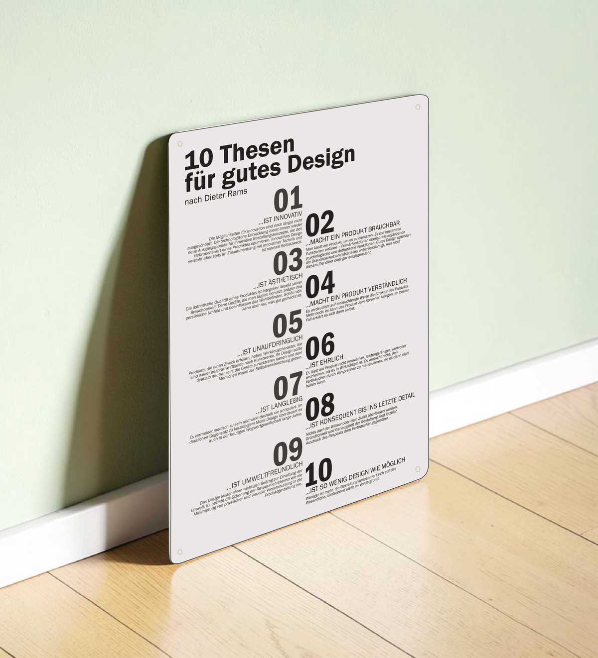 Ein hochkant ausgerichtetes, minimalistisches Metallschild im A3-Format mit den 10 Thesen für gutes Design nach Dieter Rams in deutscher Sprache. Die Typografie ist in klarem, schwarzen serifenlosen Text auf matt-weißem Hintergrund gedruckt. In den vier Ecken befinden sich dezente Vorbohrungen zur Montage.