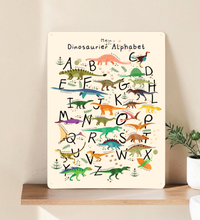 Farbenfrohes Dinosaurier ABC Poster für Kinder, dargestellt einmal als gerahmtes Papier-Poster und einmal als stabiles Metall-Blechschild mit abgerundeten Ecken und vier Bohrungen.