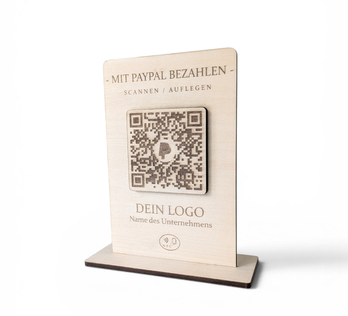 Rustikaler PayPal-Zahlungsaufsteller aus Holz mit graviertem QR-Code und NFC-Logo, der von einer Hand mit einem Smartphone berührt wird.
