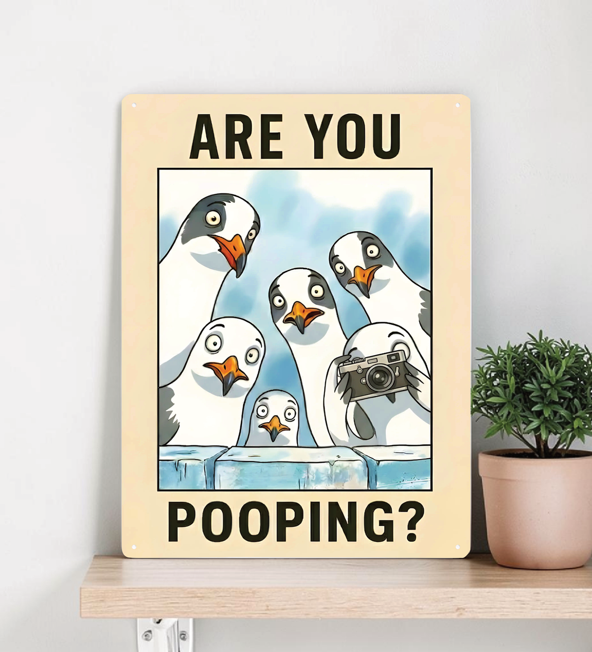 in rechteckiges, weißes Metallschild mit der Aufschrift „ARE YOU POOPING?“ oben und unten. In der Mitte blicken sechs neugierige, comicartig gezeichnete Möwen mit großen Augen über eine blaue Mauer direkt nach vorne. Das Schild steht aufrecht vor einem neutralen, hellen Hintergrund.