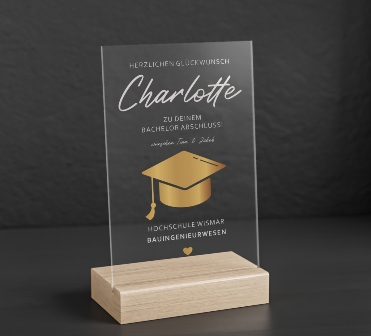 Transparenter Acrylglas-Aufsteller mit Holzsockel, personalisiert als Geschenk zum Abschluss. Zeigt goldene Doktorhut-Grafik, Namen, Studiengang und Hochschule in elegantem Design.