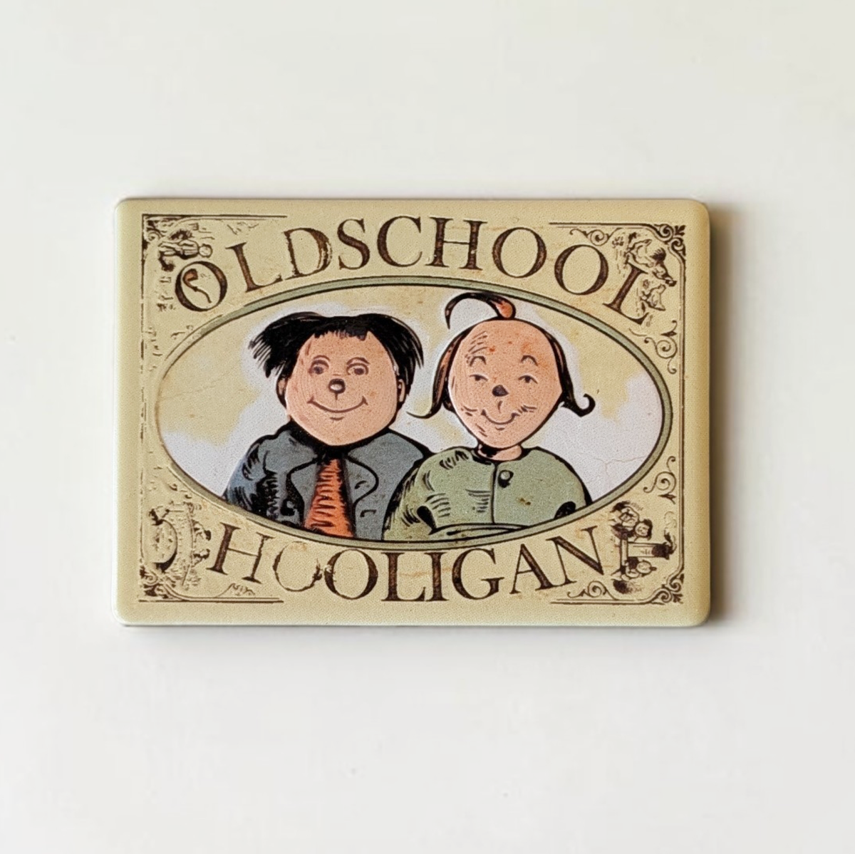 Rechteckiger Keramik-Kühlschrankmagnet (7x5 cm) im Vintage-Stil. Zu sehen ist ein ovales Medaillon mit den gezeichneten Gesichtern von Max und Moritz sowie dem Schriftzug 'OLDSCHOOL HOOLIGAN' im fühlbaren 3D-Relief.