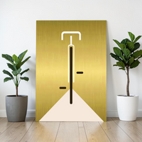 Minimalistische Bauhaus-Illustration eines Fahrrads in der Vorderansicht auf einer gebürsteten, gold-glänzenden Aluminiumplatte (Alu-Dibond). Das Design zeigt klare weiße und schwarze Linien vor einem edlen Metallhintergrund. Das Bild lehnt modern an einer weißen Wand zwischen zwei Zimmerpflanzen.