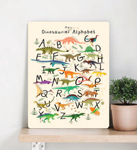 Farbenfrohes Dinosaurier ABC Poster für Kinder, dargestellt einmal als gerahmtes Papier-Poster und einmal als stabiles Metall-Blechschild mit abgerundeten Ecken und vier Bohrungen.