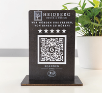Personalisierter Holzaufsteller aus 4mm Holz mit eingraviertem Logo, Wunschtext „Wir würden uns freuen, von Ihnen zu hören!“, fünf Sternen, QR-Code mit Google-Logo und NFC-Symbol auf schwarzem Standfuß.