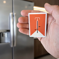 Rechteckiger, weißer Kühlschrankmagnet aus Keramik mit einem minimalistisch dargestellten Fahrrad in kräftigem Orange im Zentrum. Das Design ist schlicht, modern und sauber.