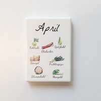 Saisonkalender Kühlschrankmagneten aus Keramik. Jeder Magnet repräsentiert einen Monat von Januar bis Dezember mit deutscher Beschriftung in geschwungener Schrift. Auf der cremefarbenen Oberfläche sind detailreiche, farbige Illustrationen von saisonalem Obst und Gemüse mit den jeweiligen Namen abgebildet.