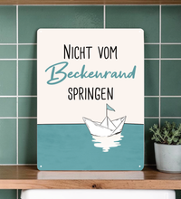 Rechteckiges Retro-Blechschild aus Metall mit dem Spruch „Nicht vom Beckenrand springen“, hochwertige Haptik, vier Eckbohrungen, vor weißem Hintergrund im Badezimmer-Stil.