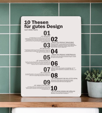 Ein hochkant ausgerichtetes, minimalistisches Metallschild im A3-Format mit den 10 Thesen für gutes Design nach Dieter Rams in deutscher Sprache. Die Typografie ist in klarem, schwarzen serifenlosen Text auf matt-weißem Hintergrund gedruckt. In den vier Ecken befinden sich dezente Vorbohrungen zur Montage.