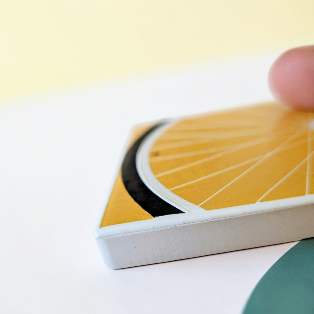Rechteckiger Keramik-Kühlschrankmagnet (7x5 cm) in warmem Gelb. Gezeigt wird ein minimalistisches Fahrradrad mit feinen weißen Speichen, einem schwarzen Reifen am unteren Rand und einer winzigen menschlichen Silhouette im spürbaren 3D-Relief.