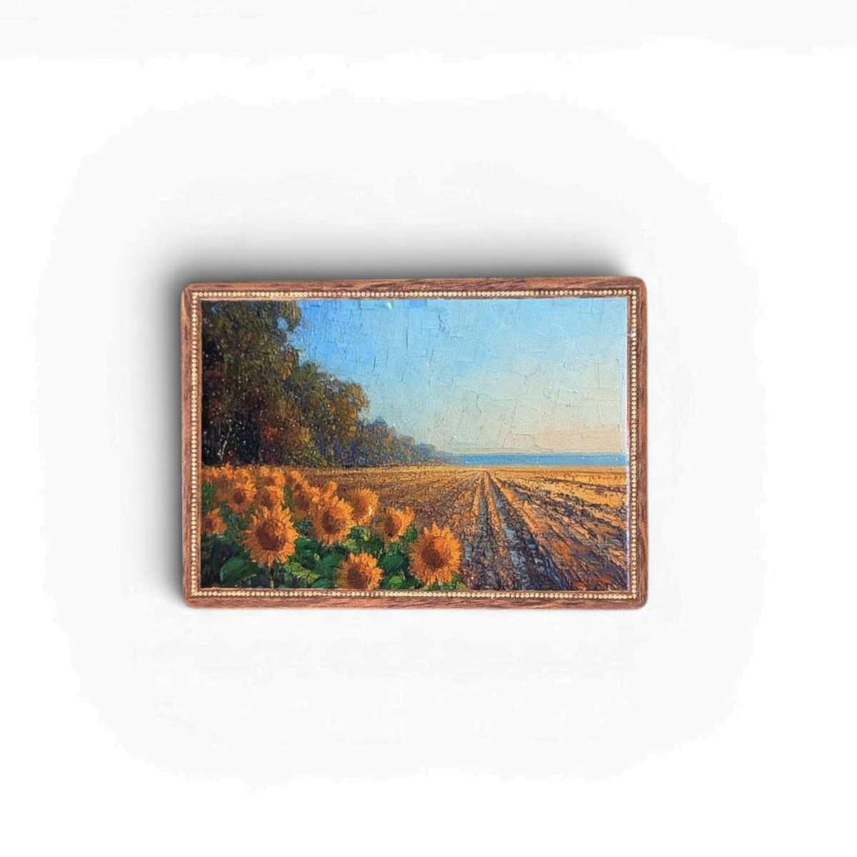 Rechteckiger Holz-Kühlschrankmagnet (7x5 cm) mit einem detailreichen Vintage-Motiv eines blühenden Sonnenblumenfeldes unter blauem Himmel. Das Bild hat einen verzierten Rand und eine fühlbare Struktur.