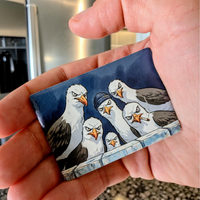 Rechteckiger Keramik-Kühlschrankmagnet (7x5 cm) im Querformat mit seidenmatter Glasur. Fünf grimmig dreinschauende Möwen, eine mit blauer Mütze und eine mit Zigarette, blicken über eine Mauer im spürbaren 3D-Relief.