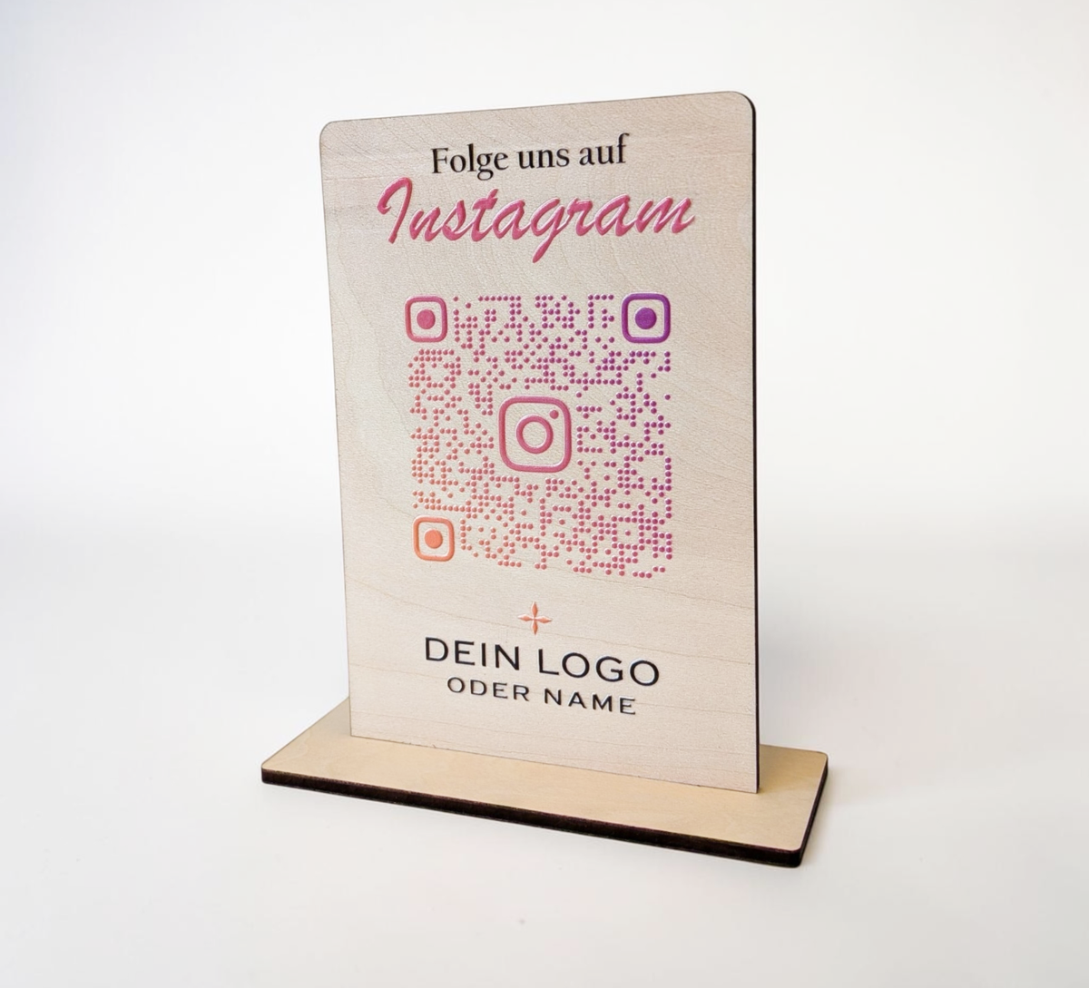 Hochkant stehender, personalisierter Tischaufsteller aus hellem Holz mit flachem Standfuß. Auf der Vorderseite sind ein Wunschtext („Folge uns auf Instagram“), ein QR-Code mit integriertem Instagram-Logo sowie ein Platzhalter für ein individuelles Firmenlogo präzise aufgedruckt.
