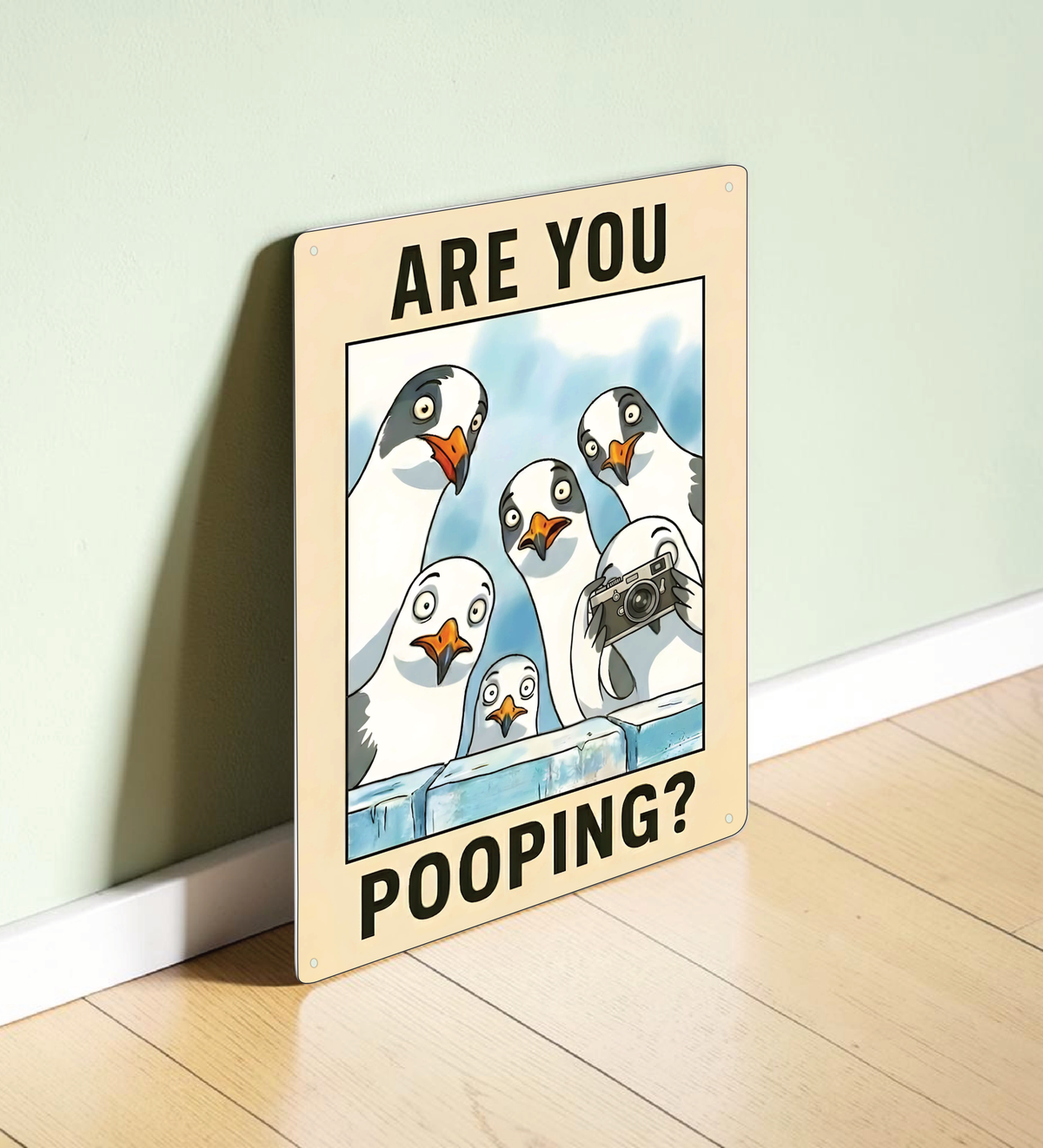 in rechteckiges, weißes Metallschild mit der Aufschrift „ARE YOU POOPING?“ oben und unten. In der Mitte blicken sechs neugierige, comicartig gezeichnete Möwen mit großen Augen über eine blaue Mauer direkt nach vorne. Das Schild steht aufrecht vor einem neutralen, hellen Hintergrund.