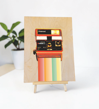 Vintage-Illustration einer klassischen Kamera im Polaroid-Stil, gedruckt auf einer hellen 9mm Birkensperrholz-Platte. Die Holzstruktur ist leicht sichtbar. Format 30x40 cm.