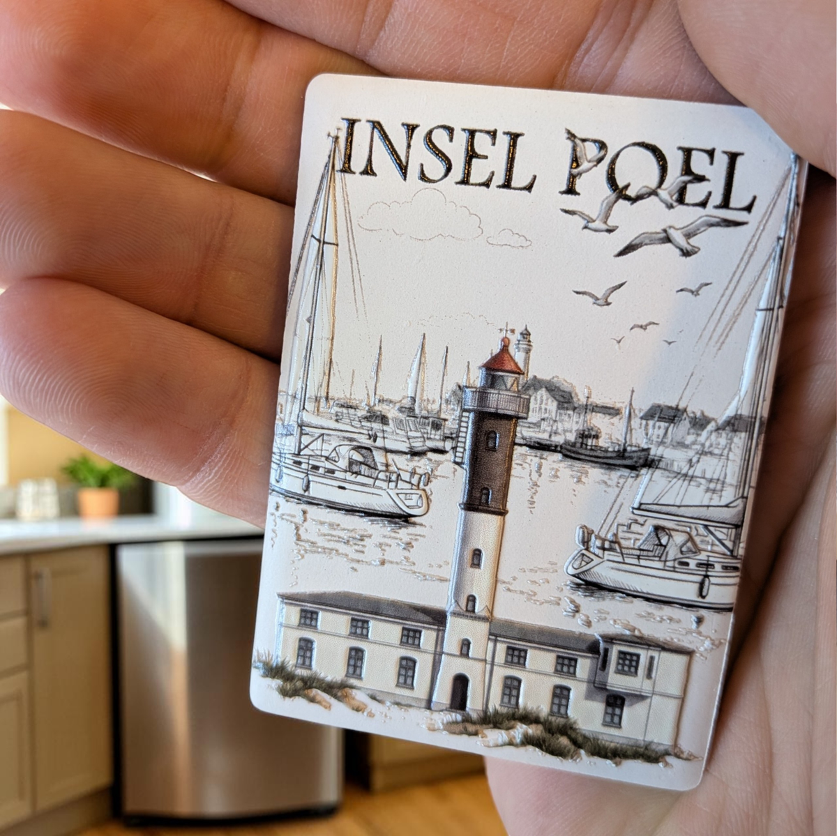 Rechteckiger Keramik-Kühlschrankmagnet (7x5 cm) mit seidenmatter Glasur. Zu sehen ist eine maritime Hafenszene der Insel Poel mit Segelbooten, Möwen und dem Timmendorfer Leuchtturm im spürbaren 3D-Relief.