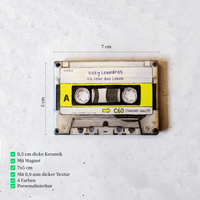 Rechteckiger Keramik-Kühlschrankmagnet (7x5 cm) im Retro-Musikkassetten-Design mit seidenmatter Glasur. Die Kassette verfügt über ein personalisierbares Beschriftungsfeld für Wunschtexte (wahlweise mit kleinem Mistelzweig) sowie spürbar erhabene Bandspulen und Kanten im 0,9 mm tiefen 3D-Relief.