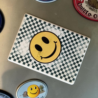 Rechteckiger weißer Keramikmagnet mit einem abstrahierten, gelben Smiley-Gesicht aus Quadraten. Die Oberfläche zeigt eine haptische Relief-Struktur und ein elegantes, seidenmattes Finish.