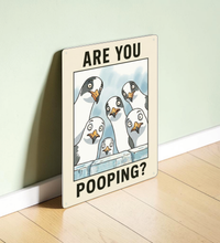 in rechteckiges, weißes Metallschild mit der Aufschrift „ARE YOU POOPING?“ oben und unten. In der Mitte blicken sechs neugierige, comicartig gezeichnete Möwen mit großen Augen über eine blaue Mauer direkt nach vorne. Das Schild steht aufrecht vor einem neutralen, hellen Hintergrund.