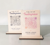 Hochkant stehender, personalisierter Tischaufsteller aus hellem Holz mit flachem Standfuß. Auf der Vorderseite sind ein Wunschtext („Folge uns auf Instagram“), ein QR-Code mit integriertem Instagram-Logo sowie ein Platzhalter für ein individuelles Firmenlogo präzise aufgedruckt.