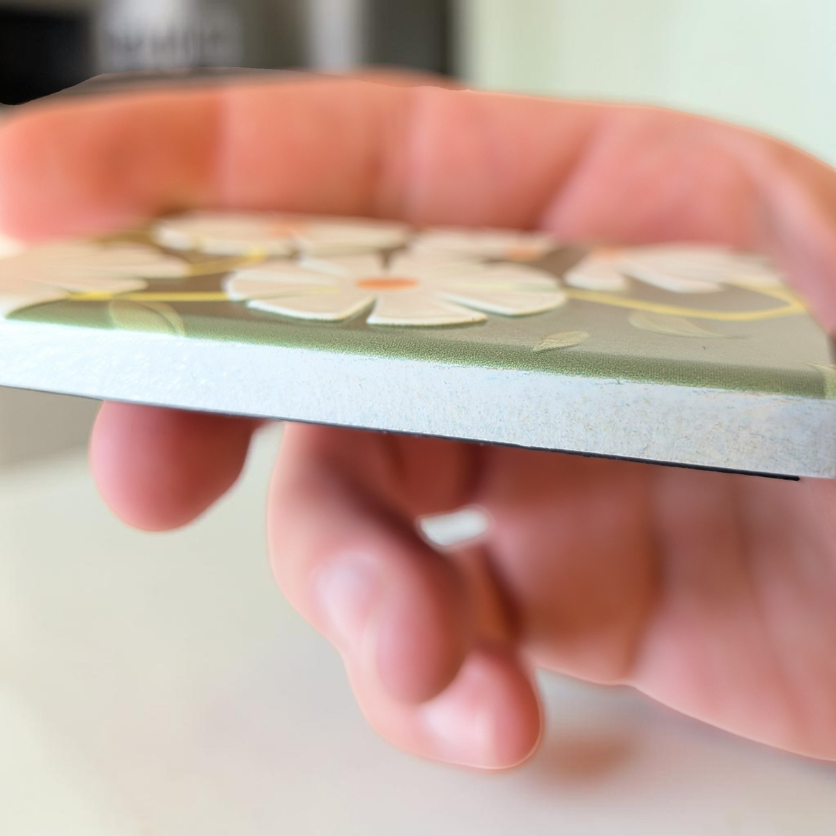 Rechteckiger Keramik-Kühlschrankmagnet (7x5 cm) in Salbeigrün mit einem spürbaren 3D-Relief aus weißen Gänseblümchen, gelben Blütenmitten und grünen Blattranken.