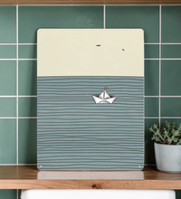 Minimalistische Illustration eines weißen Origami-Boots auf blauem, wellenförmigem Hintergrund. Erhältlich als Papierposter oder rechteckiges Metallschild mit abgerundeten Ecken.