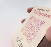 Hochkant stehender, personalisierter Tischaufsteller aus hellem Holz mit flachem Standfuß. Auf der Vorderseite sind ein Wunschtext („Folge uns auf Instagram“), ein QR-Code mit integriertem Instagram-Logo sowie ein Platzhalter für ein individuelles Firmenlogo präzise aufgedruckt.