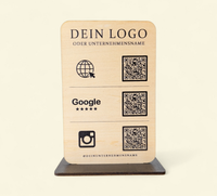 Personalisierter QR-Code Aufsteller aus hellem Holz mit schwarzem Standfuß, Logo-Gravur und drei QR-Codes für Website, Google-Bewertungen und Instagram.