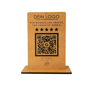 Personalisierter Holzaufsteller aus 4mm Holz mit eingraviertem Logo, Wunschtext „Wir würden uns freuen, von Ihnen zu hören!“, fünf Sternen, QR-Code mit Google-Logo und NFC-Symbol auf schwarzem Standfuß.