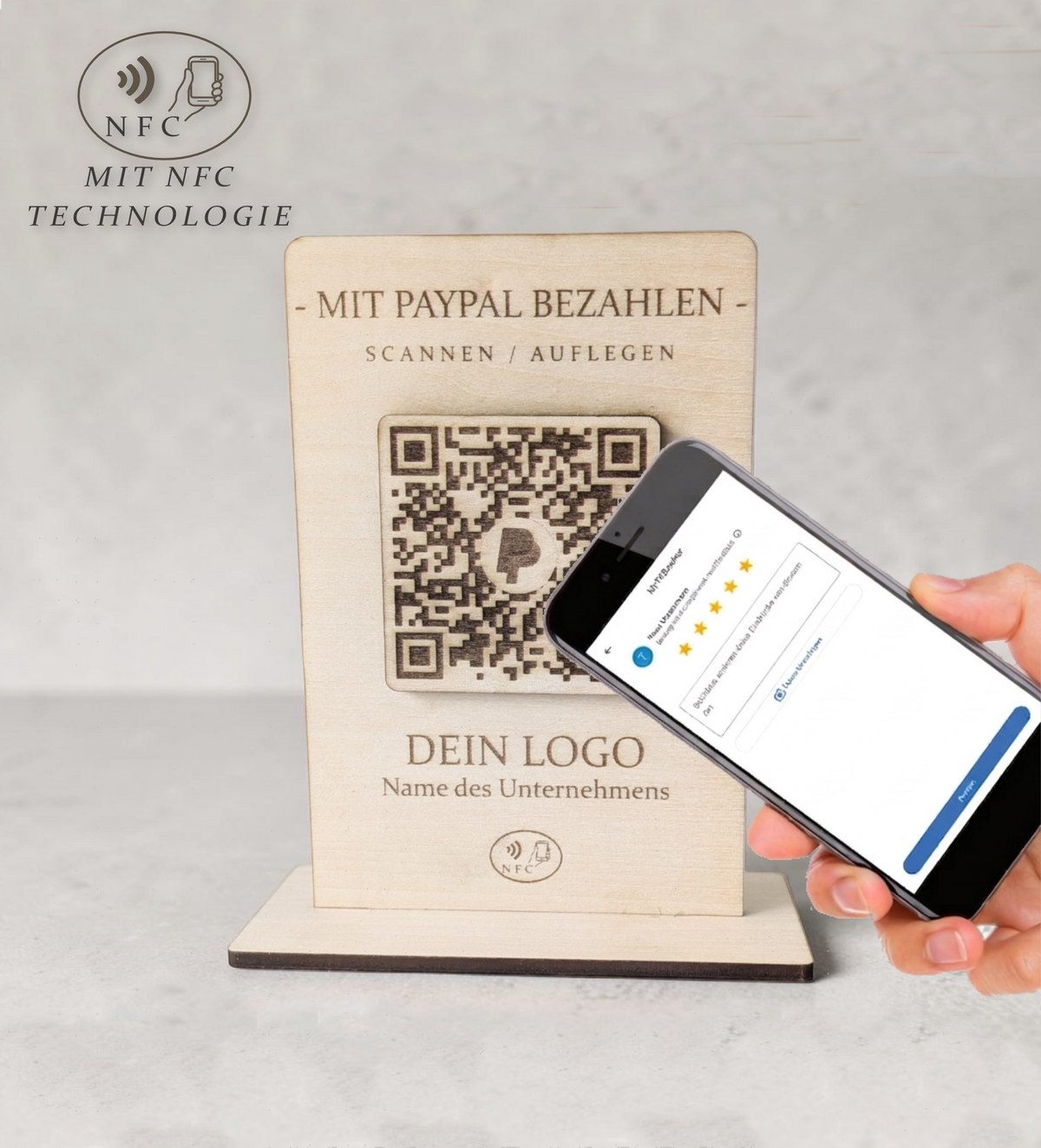 Rustikaler PayPal-Zahlungsaufsteller aus Holz mit graviertem QR-Code und NFC-Logo, der von einer Hand mit einem Smartphone berührt wird.