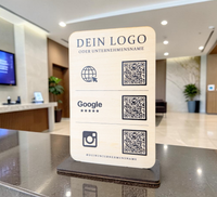 Personalisierter QR-Code Aufsteller aus hellem Holz mit schwarzem Standfuß, Logo-Gravur und drei QR-Codes für Website, Google-Bewertungen und Instagram.