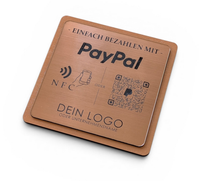 Quadratischer PayPal-Tischaufsteller aus dunklem Holz mit einer gravierten, roségold gebürsteten Kunststoffplatte. Auf der Platte sind ein QR-Code, ein NFC-Symbol und das PayPal-Logo zu sehen, perfekt geeignet für kontaktlose Zahlungen auf einer Ladentheke.