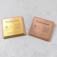 Quadratische, personalisierte Instagram-Follower-Platte aus graviertem Kunststoff in gebürsteter Optik auf Holzträger. Hochpräzise Kontrast-Gravur von NFC-Icon und QR-Code.