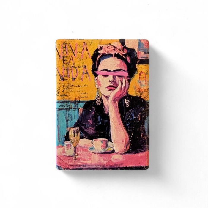 Künstlerisches Porträt einer Frau mit Blumen im Haar und einem pinkfarbenen Pinselstrich über den Augen. Im Hintergrund steht der Schriftzug „VIVA LA VIDA“ auf gelbem, strukturiertem Grund.